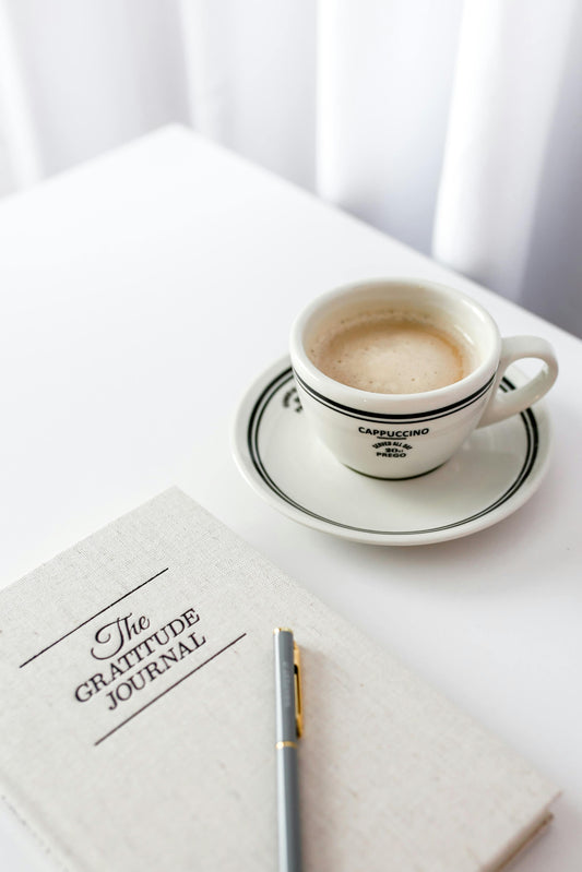 A gratitude journal on a white table with coffee